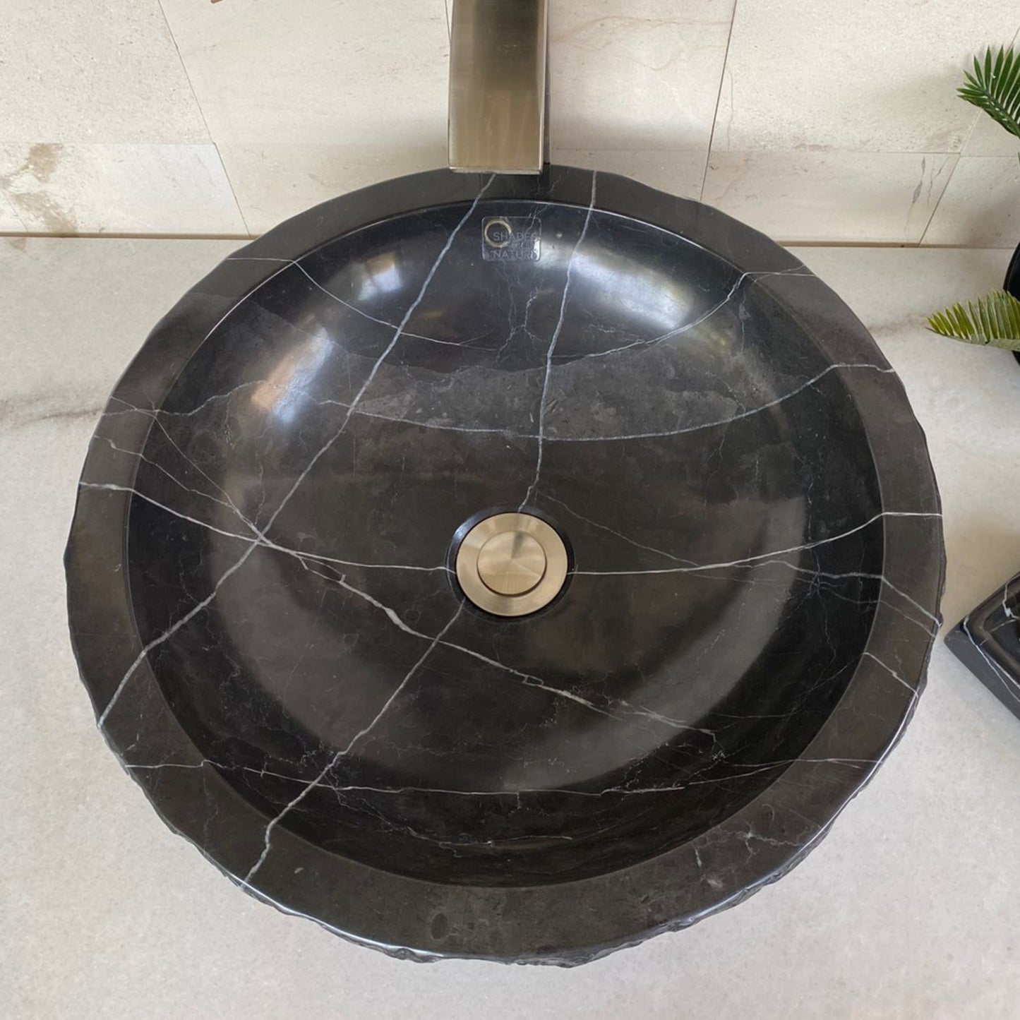 Top view of handcrafted black marble round vessel sink featuring a polished interior, natural white veining, and organic natural stone edge for luxury bathroom vanity design.