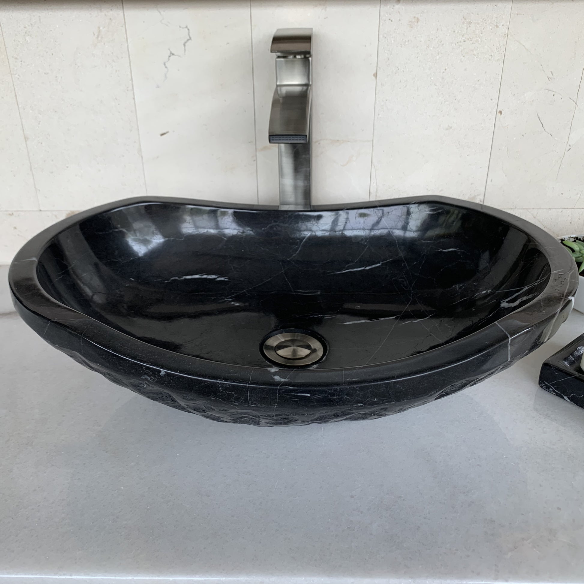 Front angle view of handcrafted black marble oval vessel sink featuring polished interior basin, elegant oval silhouette, natural white marble veining, and luxury above-counter bathroom vanity design.