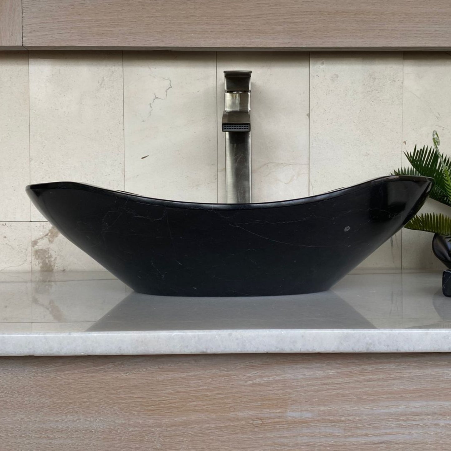 Handcrafted black marble oval vessel sink with polished interior, elegant curved silhouette, natural marble veining, and luxury above-counter bathroom vanity design.