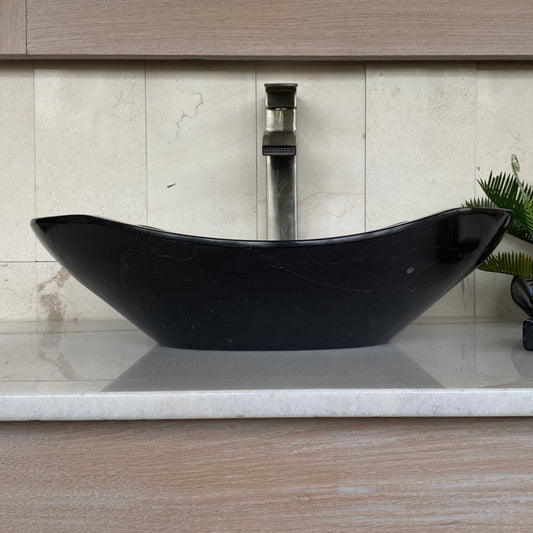 Handcrafted black marble oval vessel sink with polished interior, elegant curved silhouette, natural marble veining, and luxury above-counter bathroom vanity design.