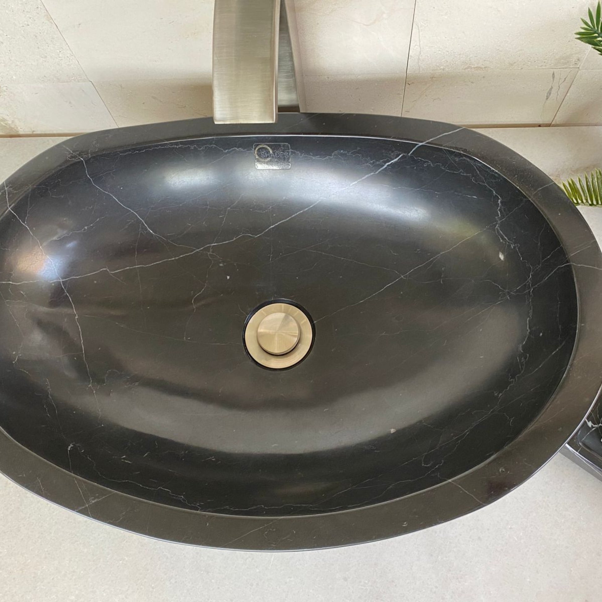 Top view of handcrafted black marble oval vessel sink featuring polished interior basin, natural white marble veining, oval designer shape, and standard center drain for luxury bathroom vanity installation.