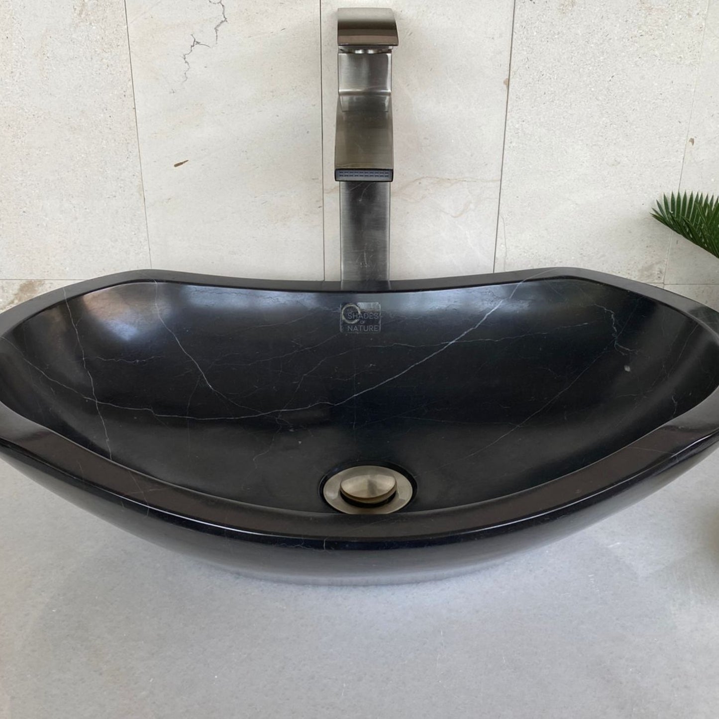 Front angle view of handcrafted black marble oval vessel sink featuring polished interior basin, elegant sculpted oval silhouette, natural marble veining, and luxury above-counter bathroom vanity design.