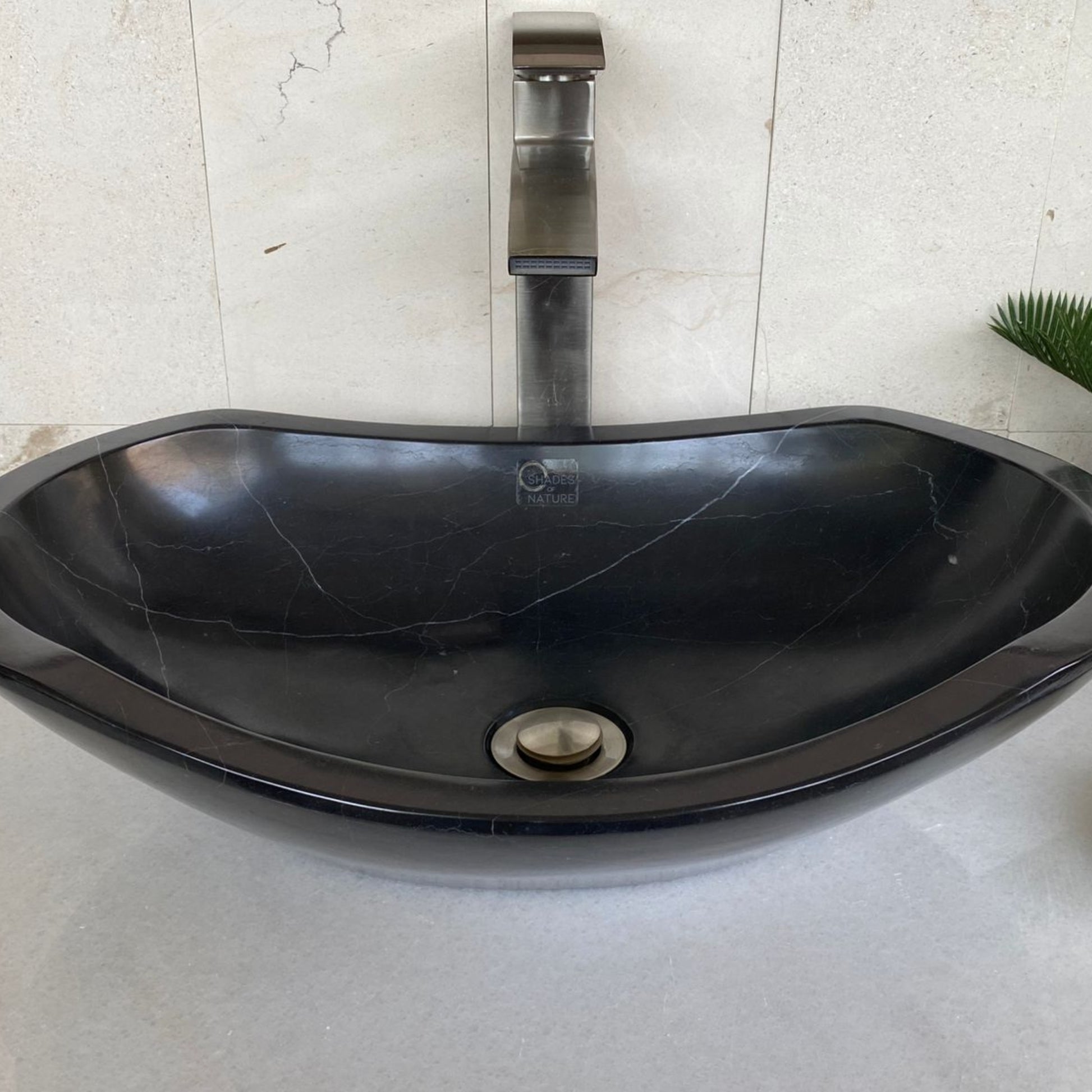 Front angle view of handcrafted black marble oval vessel sink featuring polished interior basin, elegant sculpted oval silhouette, natural marble veining, and luxury above-counter bathroom vanity design.