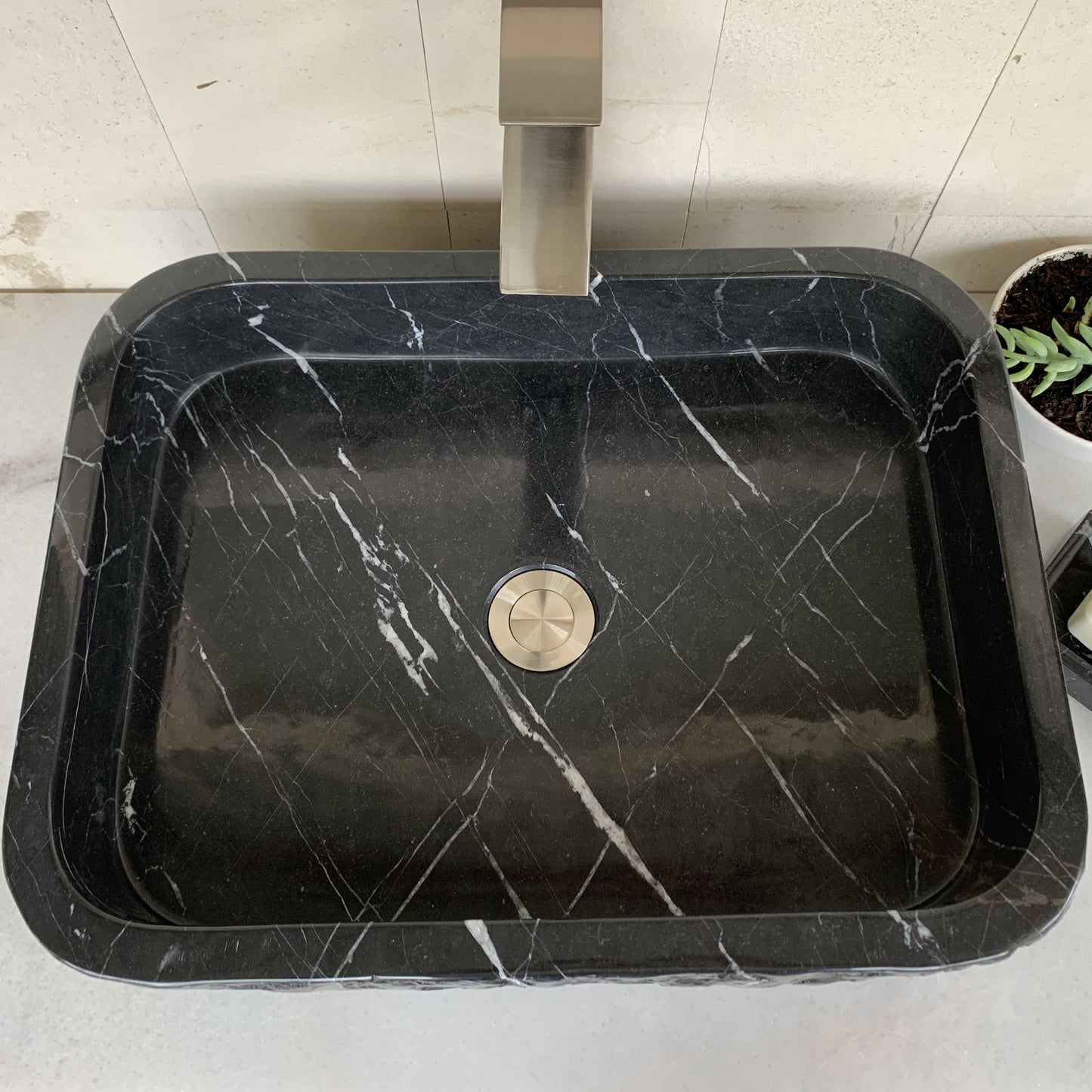 Top view of handcrafted black marble rectangle vessel sink featuring polished interior, natural white marble veining, rectangular basin design, and standard center drain for luxury bathroom vanity installation.