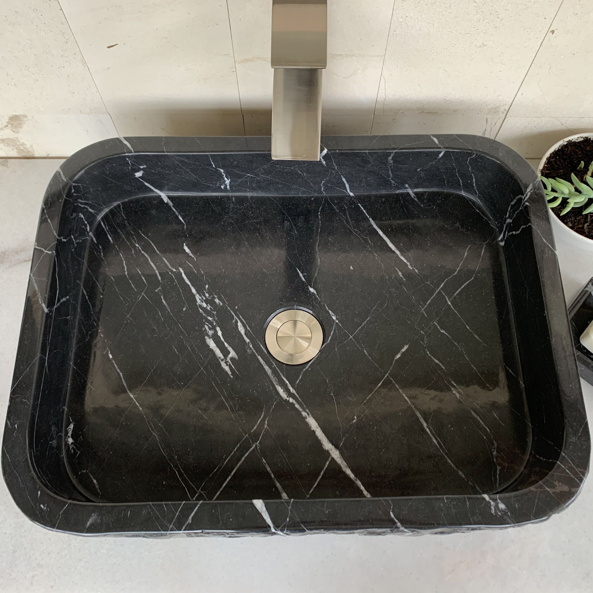 Top view of handcrafted black marble rectangle vessel sink featuring polished interior, natural white marble veining, rectangular basin design, and standard center drain for luxury bathroom vanity installation.