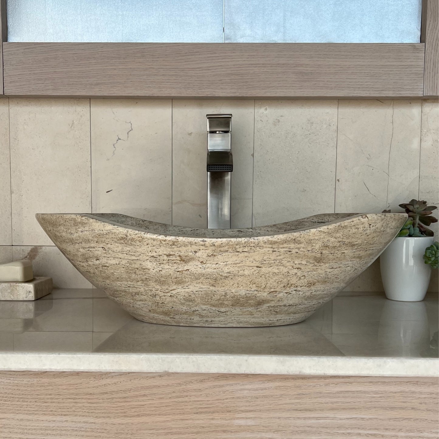 Front view of a smooth, fully polished natural stone oval vessel sink, displayed in a contemporary bathroom vanity setting.