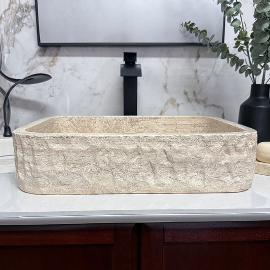Front view of a rectangular travertine vessel sink with a rustic chiseled exterior finish and clean straight-line profile.