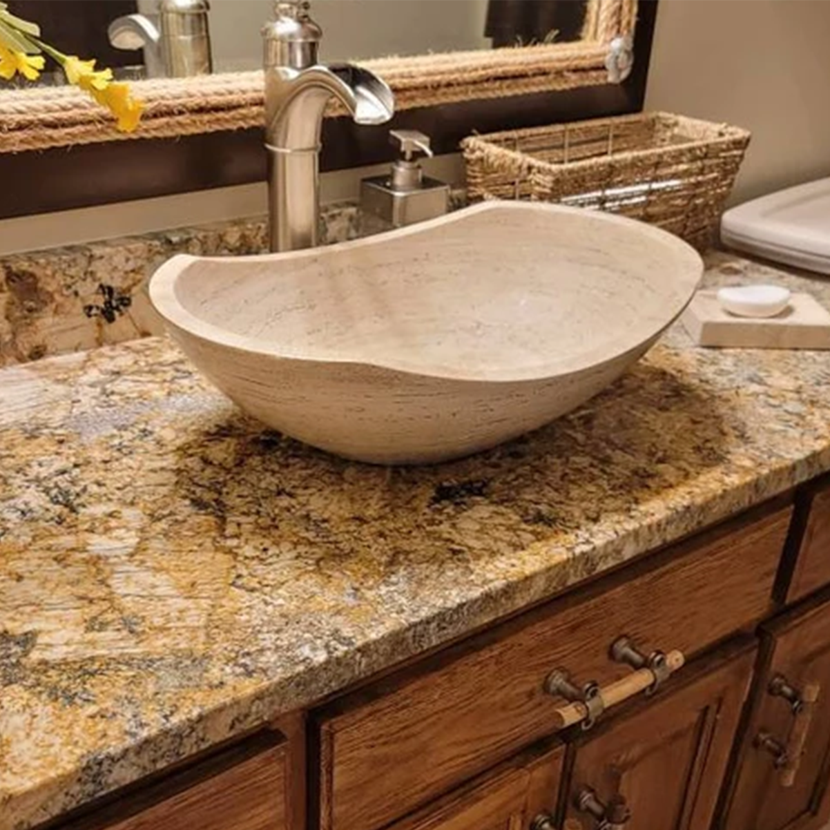 Polished travertine oval vessel sink with a unique curved rim, showcased in a real designer home bathroom setting on a stone vanity