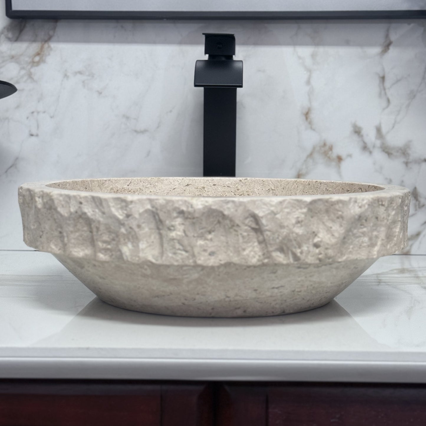 Round tan travertine vessel sink with chiseled rim for natural stone bathroom vanity.