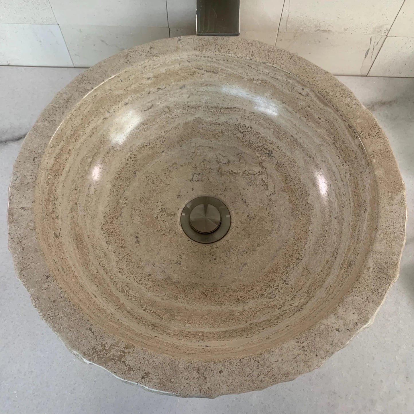 Natural travertine stone wash basin from above, revealing the unique organic veining patterns of the polished inner bowl and a chiseled exterior.
