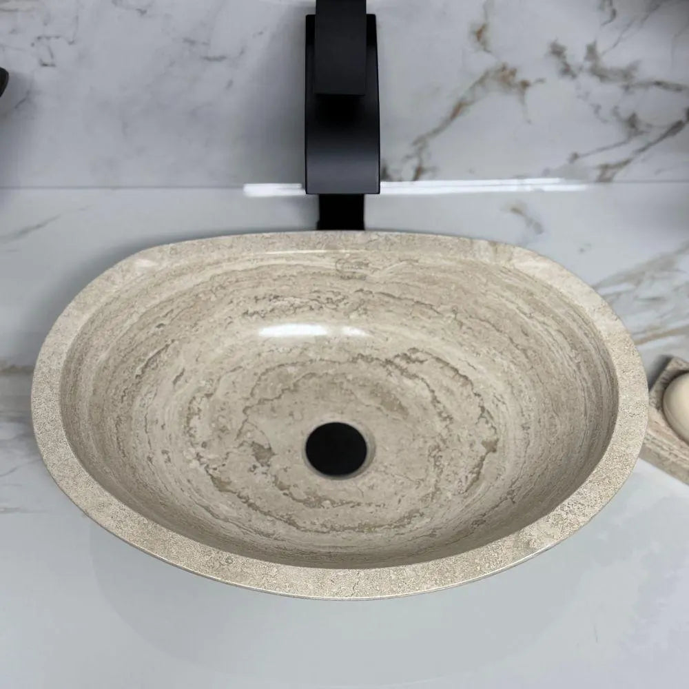 Overhead top-down view looking into an oval polished tan travertine vessel sink, showcasing the smooth glossy finish and beautiful organic concentric grain patterns of the natural stone basin.